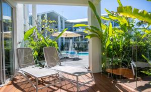 a balcony with two chairs and a swimming pool at Beaches Holiday Apartments - Official Onsite Reception & Check In in Port Douglas