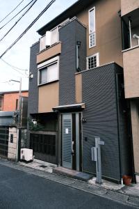 ein schwarzes Gebäude mit einer Tür auf einer Straße in der Unterkunft Muji Arashiyama Villa 無時嵐1階2階賃貸し 駅まで徒歩2分 in Kyoto