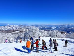 um grupo de pessoas em pé no topo de uma montanha coberta de neve em Minshuku Kojima em Nozawa Onsen