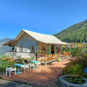 una yurta con mesas y bancos frente a ella en Moksham Himalayan Campsite Pangot, en Nainital