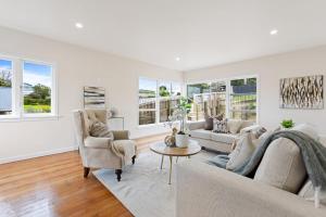 Una sala de estar con un sofá y dos sillas y una mesa. en Sun-Soaked Holiday Home Close to Beach, en Auckland