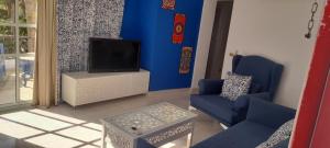 Delta Sharm appartment Shahrazad في شرم الشيخ: غرفة معيشة مع تلفزيون وجدار أزرق