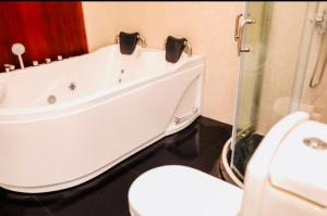 a bathroom with a white tub and a toilet at Kolonne RIverside Garden Hotel in Avissawella