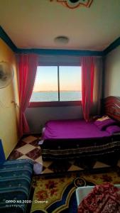 a bedroom with a purple bed and a window at الضيافة in Shakshuk
