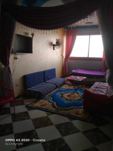 a living room with a blue couch and a window at الضيافة in Shakshuk
