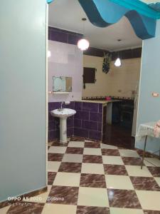 ein Badezimmer mit einem karierten Boden und einem Waschbecken in der Unterkunft الضيافة in Shakshuk