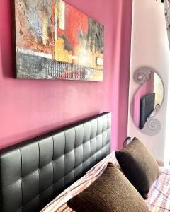 1 dormitorio con pared de color rosa, cama y espejo en Suite Gaia, en Bari