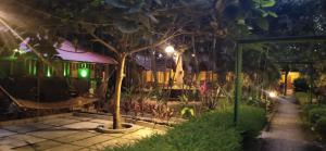 einen Garten in der Nacht mit einer Hängematte und einem Baum in der Unterkunft SAVITHRI INN Cottages in Varkala