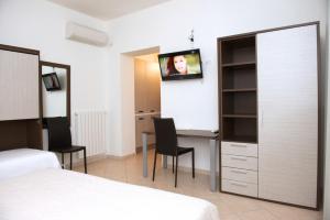 a bedroom with a bed and a desk with a tv on the wall at Domo - Guest-House Il Nespolo Fiorito in Orosei