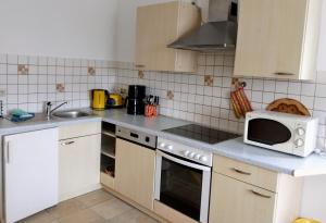 a kitchen with white cabinets and a white microwave at Ferienwohnung Lindeneck in Neusitz