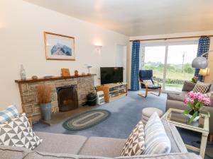 a living room with a couch and a fireplace at Hefo'r Grug in Pwllheli