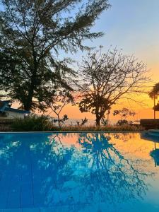 a swimming pool with a sunset in the background at 7SEAS Cottages in Gili Islands