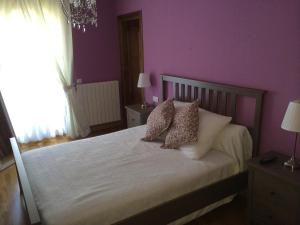 - une chambre avec des murs violets et un lit avec des oreillers dans l'établissement El Porton de la Huebra, à Vecinos