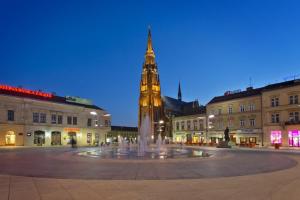 a clock tower in the middle of a city with a fountain at Hostel OS in Osijek