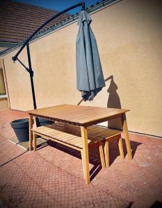 a wooden picnic table with an umbrella next to a building at Maison de caractère in Crancey +3 photos