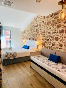 1 dormitorio con 2 camas y pared de piedra en Soléa House Hotel Boutique en Benicàssim