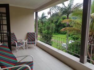 a balcony with chairs and a view of a garden at Eden Wilds Unit 8 in Port Edward