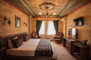 a bedroom with a bed and a couch and a tv at Olivia Cave Hotel in Göreme