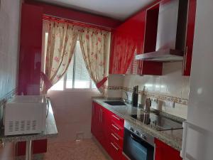 eine Küche mit roten Schränken und einem Fenster in der Unterkunft Corazón de Aguilar in Aguilar de la Frontera