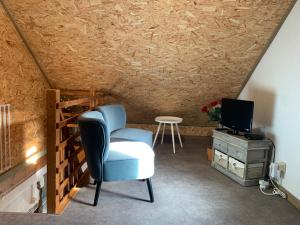 a living room with a blue chair and a television at Le p'tit gîte d'Enhet in Ciney