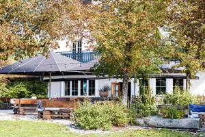 a white house with a table and an umbrella at Hotel Schmiedhubers in Engelsberg