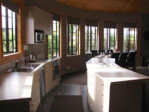 una cocina con armarios blancos, encimeras y ventanas en Ngauruhoe Yurt - Ohakune Holiday Home en Ohakune