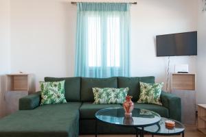 un soggiorno con divano verde e tavolo in vetro di Villa Marmara a Cherronisos
