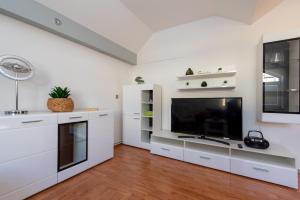 uma cozinha com armários brancos e uma televisão de ecrã plano em Apartman Lega - Daruvar em Daruvar