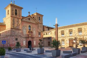 un gran edificio con una iglesia con una torre de reloj en CASA LA TERCIA, en Herencia