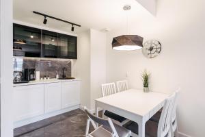 a white kitchen with a white table and chairs at Apartament Baltic Plaza 316 in Kołobrzeg