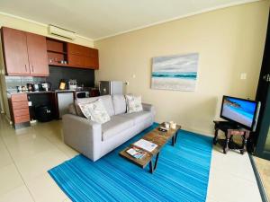 a living room with a couch and a table and a television at The Waves, 302 Quayside Point Waterfront in Durban