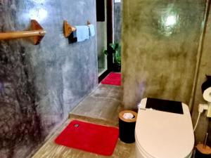 a bathroom with a toilet and two red mats at shakabrah beach club cottage in General Luna