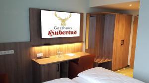 Schlafzimmer mit einem Schreibtisch und einem TV an der Wand in der Unterkunft Hotel & Restaurant Hubertus Sehnde in Sehnde