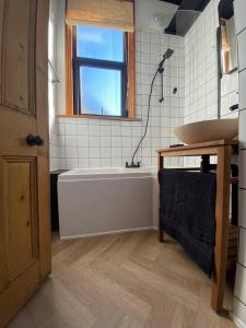 a bathroom with a bath tub and a sink at Edwardian Villa by the Sea Coastal Walks King Beds in Walton-on-the-Naze