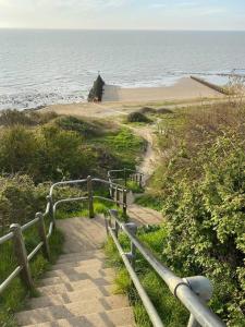 a staircase leading down to a beach with the ocean at Edwardian Villa by the Sea Coastal Walks King Beds in Walton-on-the-Naze
