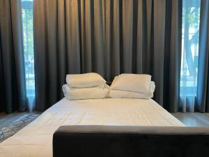un letto con lenzuola e cuscini bianchi in una stanza con finestre di Daukanto 5 a Kaunas