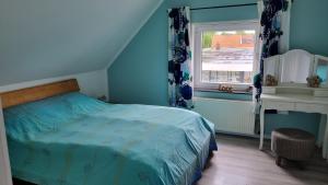 a blue bedroom with a bed and a window at Nordseeblick 2 in Carolinensiel