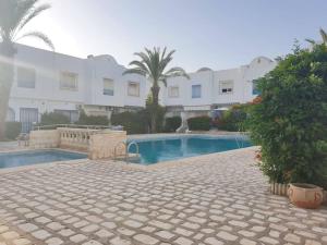 a swimming pool in front of a building at Joli duplex à Hammamet dans résidence avec piscine in Hammamet