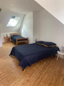 een slaapkamer met een blauw bed en een houten vloer bij Maison proche Mont Saint Michel in Beauvoir