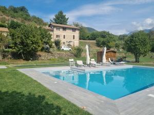 a swimming pool with chairs and a house at Agriturismo La Cascina dei Chicchi in Bagnone