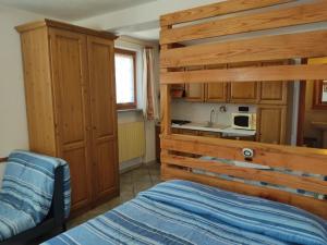 a bedroom with a bed and a kitchen with a sink at Residenza L'Teit in Sestriere
