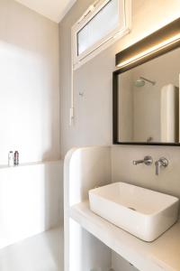 Baño blanco con lavabo y espejo en Yalos mykonos 3 bedroom Luxury home in Mykonos Town with Sea & Sunset view en Tagou