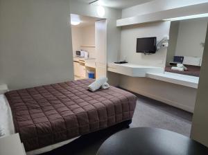 a small hotel room with a bed and a mirror at Hume Inn Motel Albury CBD in Albury