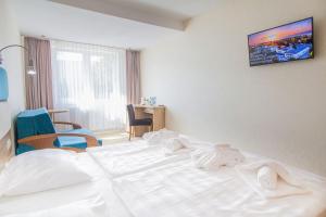 Cama blanca en habitación con TV en la pared en Imperiall Resort & MediSpa, en Ustronie Morskie