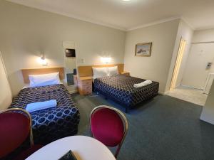 a hotel room with two beds and a table and chairs at Hume Inn Motel Albury CBD in Albury