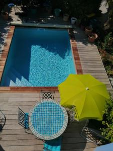 una piscina con sombrilla verde y 2 sillas en L'Ecrin d'Azur en Sanary-sur-Mer