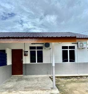 a small white house with a red door at Azfar Homestay in Kangar