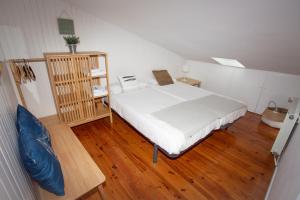 1 dormitorio con cama blanca y suelo de madera en LA MARINA amplio apartamento en pleno centro de Hondarribia, en Hondarribia