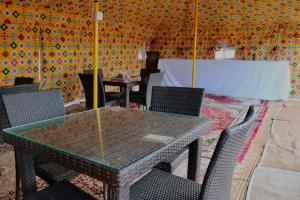 a dining room with a glass table and chairs at Rashid Desert Private Camp in Badīyah