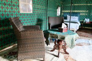 Pokój z 2 krzesłami, stołem i łóżkiem w obiekcie Rashid Desert Private Camp w mieście Badīyah